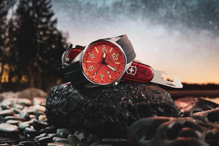 Rugged watch with a striking red dial and a Swiss knife on a wet stone captures the essence of adventure in lifestyle product photography services