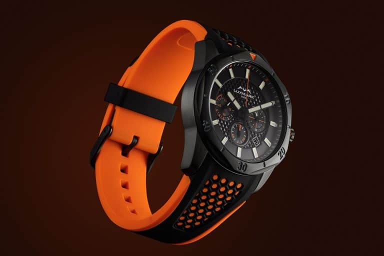 Striking watch with a black dial and an eye catching bright orange strap stands out on a dark background in packshot photography