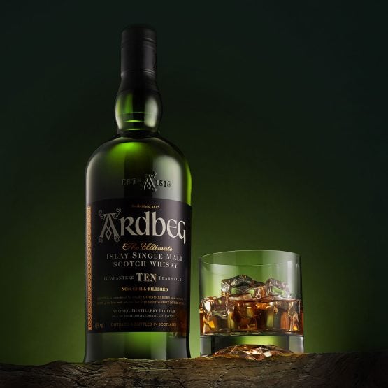 Whiskey bottle and glass ad on lush dark green in commercial lifestyle photography