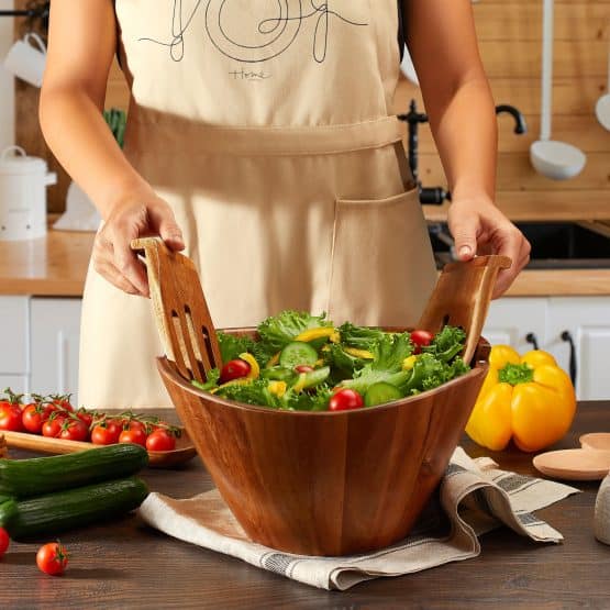 Woman in kitchen stirring salad in wooden bowl captured in lifestyle product photography services