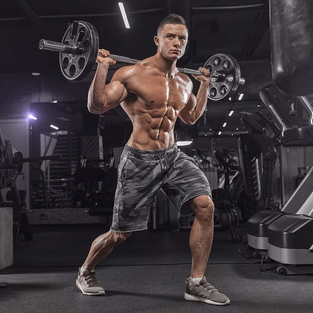 Young muscular man doing exercises with resistance bands against a dark gym background in advertising photography before