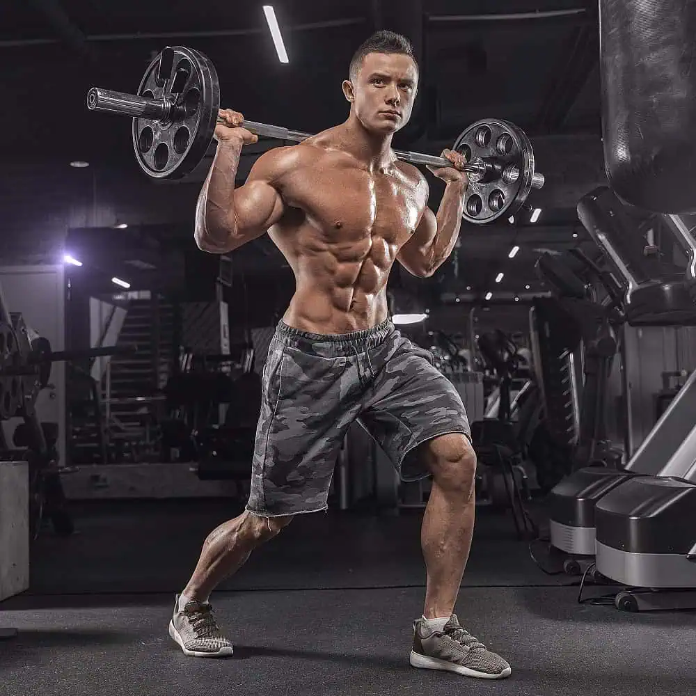 Young muscular man doing exercises with resistance bands against a dark gym background in advertising photography before